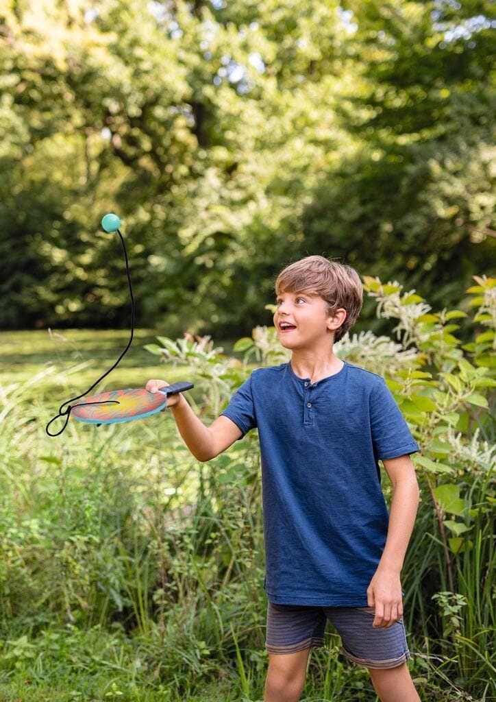 jongen speelt met paddle bal met koord op vakantie