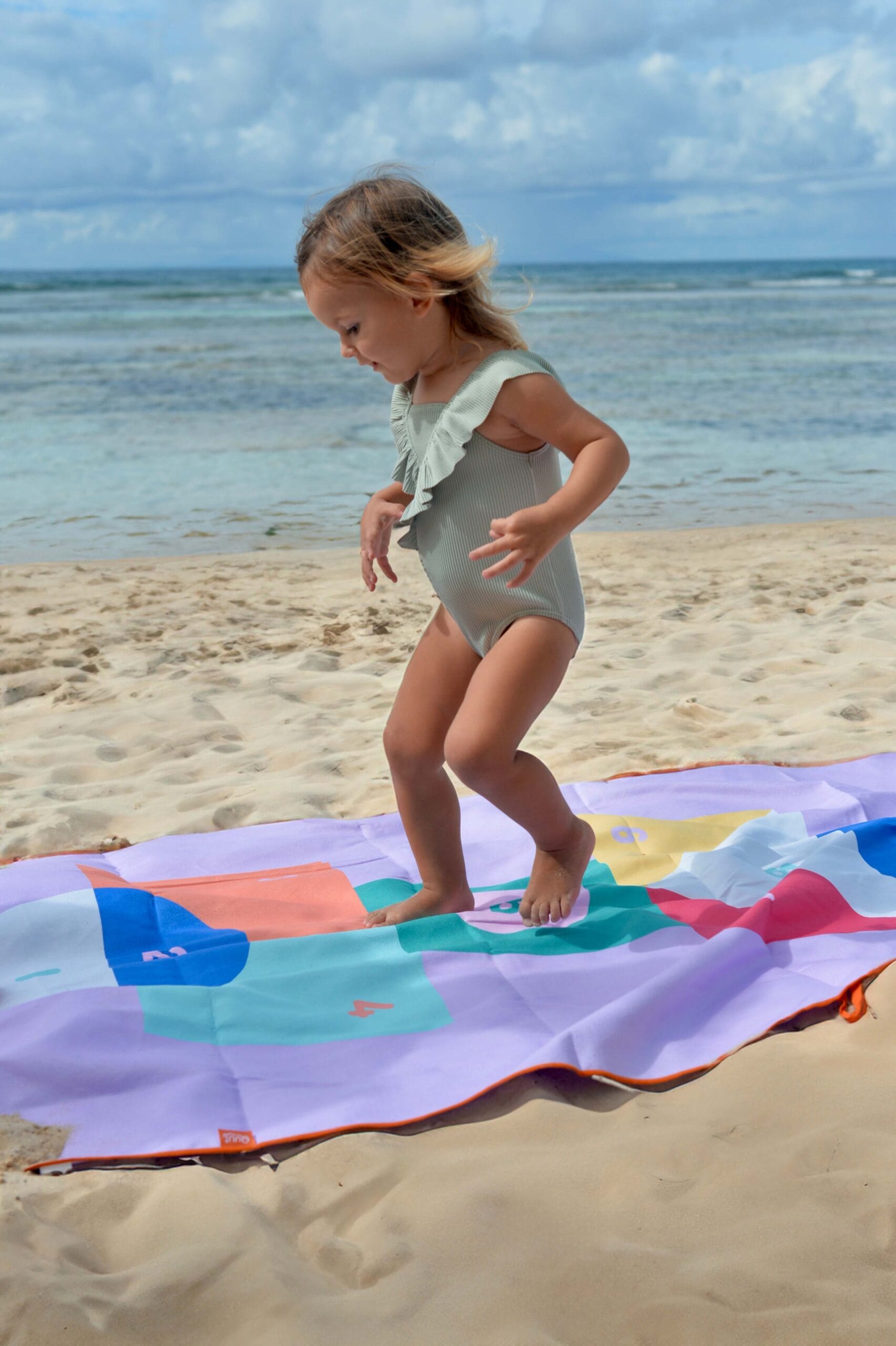 quut speel- en strandhanddoek voor kinderen. Hinkelspel, meisje hinkelt op de handdoek op het strand